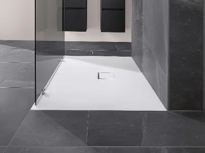 Une salle de bains moderne avec un receveur de douche Squaro Infinity, une cabine de douche en verre et un carrelage gris.