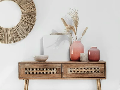 Une console en bois avec des vases Perlemor et un miroir rond.