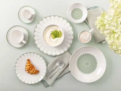 Table setting with Villeroy & Boch Fleur Vert plates Table setting with Villeroy & Boch Fleur Vert plates, croissant, yogurt, coffee, and white flowers on a light green background.