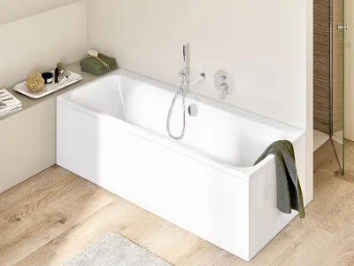 Ein modernes Badezimmer mit einer weißen rechteckigen Architectura Badewanne, über deren Rand ein grünes Handtuch hängt. Der Raum hat einen hellen Holzboden und eine beige Wand. Neben der Badewanne steht ein Regal mit Toilettenartikeln.