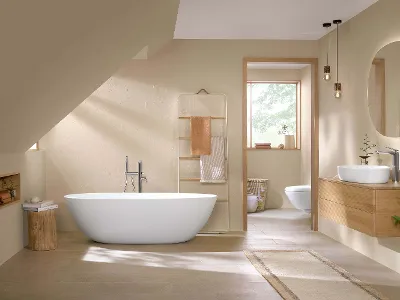 Modernes Badezimmer-Interieur mit freistehender Badewanne, Holzwaschtisch mit Aufsatzwaschbecken, Toilette, runden Spiegeln und beigen Wänden, mit natürlichem Licht, das durch eine offene Tür einfällt.