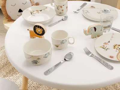 Een gedekte tafel in de kinderkamer met Boho-Kids servies, bestek en glazen in een dierenthema in pastelkleuren.