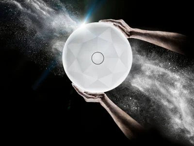 Gros plan sur deux mains tenant un lavabo blanc lumineux sur un fond sombre avec des particules blanches tourbillonnantes.