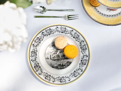 Une élégante décoration de table avec une assiette pour le petit-déjeuner décorée de la collection Audun et deux macarons.