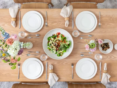 Spring Table Setting – For Me Collection from Above Vue de dessus d’une table printanière pour quatre personnes sur une table en bois. L’ensemble inclut la collection For Me de Villeroy & Boch : assiettes plates, assiettes à déjeuner, bols et un grand saladier. Accompagné des élégants couverts Piemont et d’un bouquet de fleurs printanières, l’ensemble est léger, décontracté et accueillant.