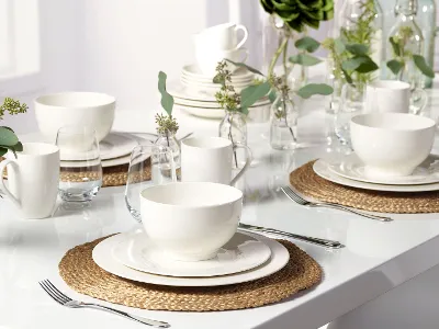 Un élégant ensemble de vaisselle blanche de la collection Basic White de Villeroy & Boch sur une table avec des sets de table décoratifs et des plantes vertes.