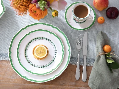 Een rustiek gedekte tafel met French Garden borden, een heerlijk citroendessert, een kopje koffie en verse bloemen.