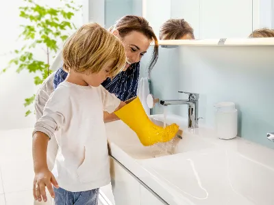 Una donna e un bambino lavano uno stivale di gomma giallo in un lavabo Subway 3.0.