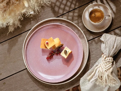 Ein rosa Perlemor Frühstücksteller von like. by Villeroy & Boch mit einem Stück Käse und einer Tasse Kaffee.