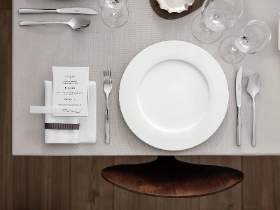 Une décoration de table pour une fête élégante avec une assiette Royal, un menu, des couverts de table Piemont et des verres vus du dessus.