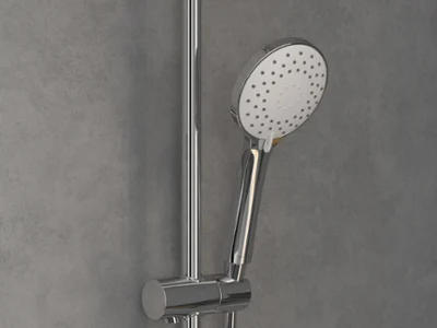 Une pomme de douchette à main dorée, montée sur un rail vertical devant un mur gris.