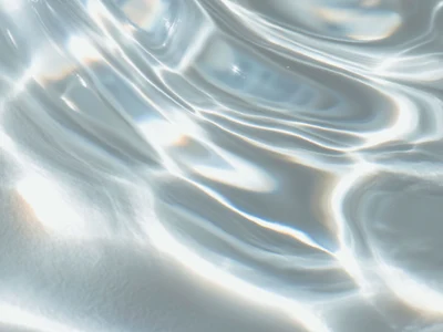 Reflection on rippling water surface Sunlight is reflected by the gentle waves of the clear water, creating bright, wavy patterns on the surface.