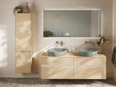 Moderne Boho-bad fra Villeroy & Boch med veggmontert Venticello-toalett og bidé på rullesteinsgulv. En dekorativ plante og en kurv står på en trehylle over.