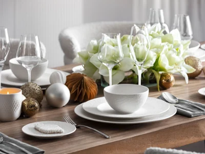 Elegant table setting with Manufacture dinnerware Elegant table setting with Manufacture dinnerware, glassware, silverware, and a centerpiece of white flowers and decorative ornaments.