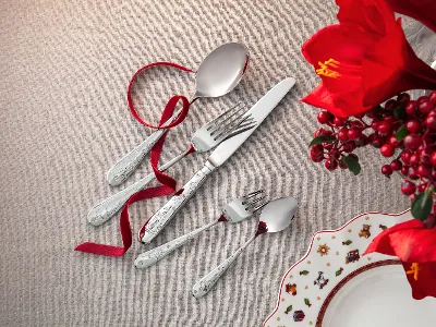 Ein Toy’s Delight Besteckset bestehend aus Löffel, Gabel, Messer und zwei kleinen Löffeln, arrangiert auf einem beigen Tuch mit roter Schleife.