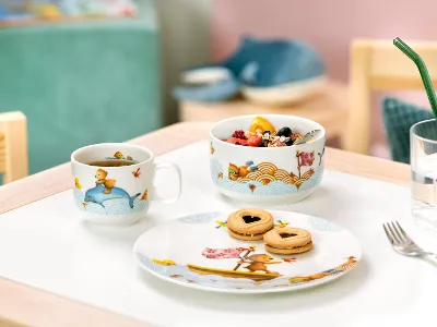 Un ensemble pour le petit-déjeuner Kiddy Bears avec une tasse décorée, une coupe à fruits et une assiette de biscuits sur une table.