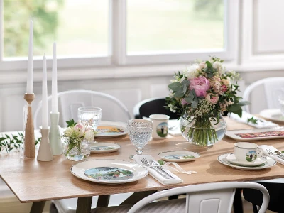 A romantically set table with Design Naif dinnerware and NewMoon flatware as well as flowers and candles.