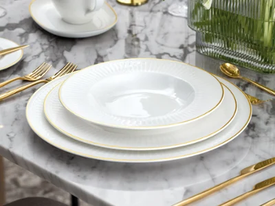 Château Septfontaines sur une table Un service de table formel avec des assiettes blanches, des couverts en or, une saucière blanche et une composition florale sur une table en marbre.