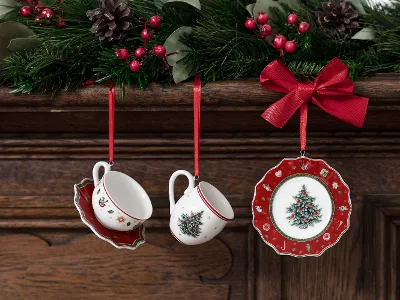 Toy‘s Delight Ornamente, hängen an roten Bändern von einem mit Mistelzweigen und Beeren geschmückten Holzkaminsims.