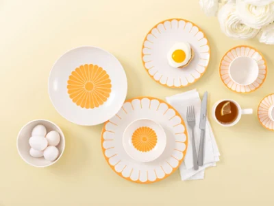 Table setting with Villeroy & Boch Fleur Soleil plates Table setting with Villeroy & Boch Fleur Soleil plates, eggs, tea with a slice of lemon, and white flowers on a light yellow background.