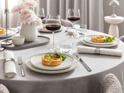 Elegant table set for four featuring Afina porcelain dinnerware and Maxima red wine glasses filled with wine. Served with food in a refined, modern dining atmosphere.