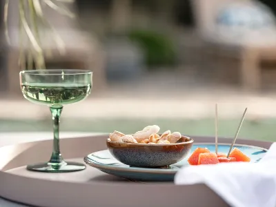 Un verre Like Sage, un bol de crackers Lave et des tranches d’orange sur un plateau à l’extérieur.