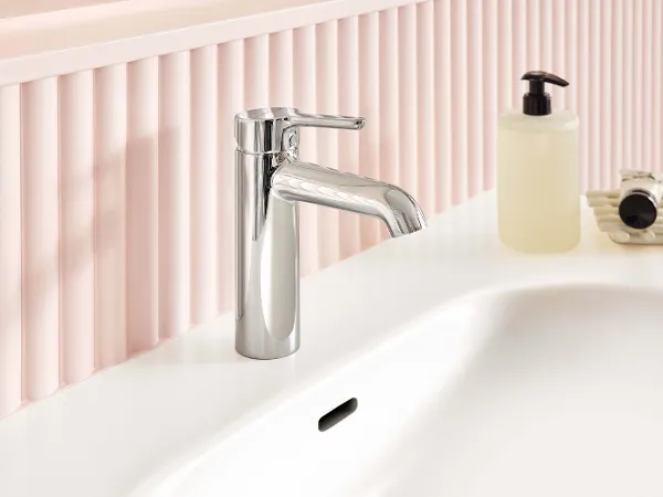 Krom vaskarmatur i et blødt, rundt design fra Skyla badeværelseskollektionen i kombination med Skyla vask - begge i et pastelfarvet miljø i rosa nuancer.