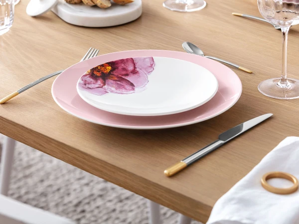 Een minimalistische eettafel met elegante Rose Garden borden met een bloemenpatroon, aangevuld met modern, goudkleurig Ella bestek.