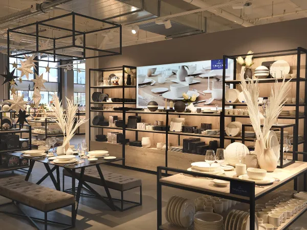 Un intérieur de magasin moderne avec une grande variété d’ustensiles en céramique Un intérieur de magasin moderne avec de la vaisselle en céramique variée et des décorations sur des étagères en métal noir et des tables avec un éclairage doux.