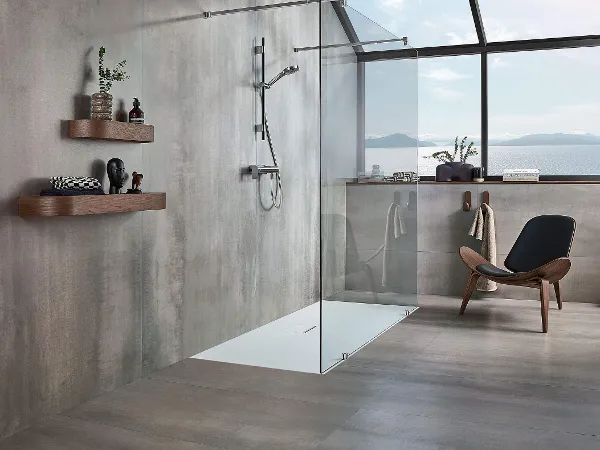 Un bagno moderno e grigio con piatto doccia Squaro Infinity e sedia marrone.