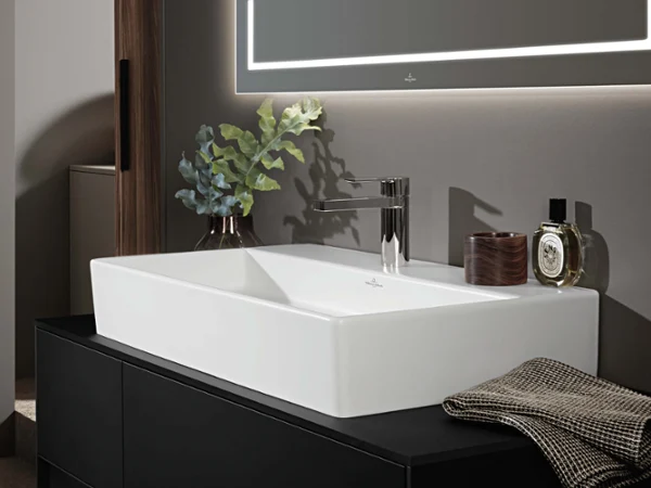 Minimalist Memento 2.0 single washbasin in glossy white, set on a dark countertop with modern accessories for a stylish bathroom look.