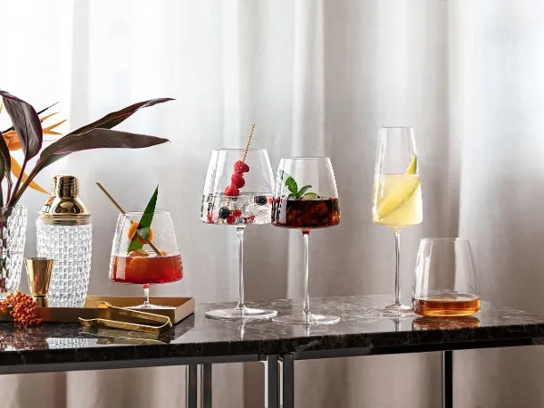 Différents cocktails servis dans d’élégants verres MetroChic sur une table en marbre à côté d’une plante.