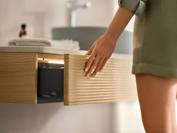 Dans une salle de bains, une femme ouvre un tiroir de console de la collection de meubles de salle de bains Antao de Villeroy & Boch.