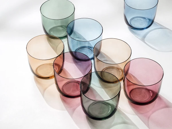 Water glasses in different colors from like. by Villeroy & Boch arranged on a white surface.