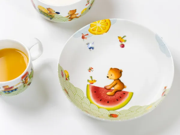 Un ensemble de vaisselle pour enfants Hungry as a bear comprenant une assiette, une tasse et un plat creux ainsi que du jus d’orange.