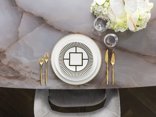 Stylish dinnerware with elegant MetroChic crockery, gold cutlery and a floral centrepiece on a marble table.