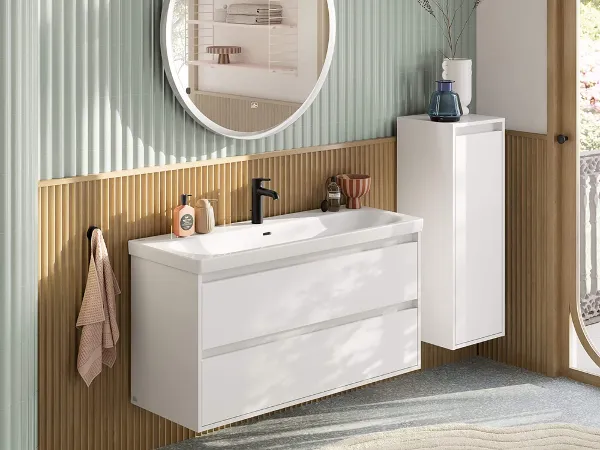 Generøst vaskeområde i hvidt med Villeroy & Boch Skyla-kollektionen. Generøst, moderne vaskeområde i pastelfarver bestående af vaskeskab med hvidt underskab, rundt, belyst spejl, sideskab og sort armatur fra Skyla-badeværelseskollektionen.