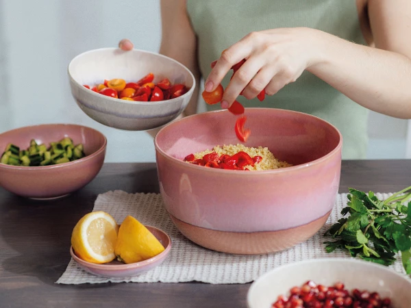 Een vrouw bereidt een couscous-salade in een Perlemor saladeschaal van like. by Villeroy & Boch.