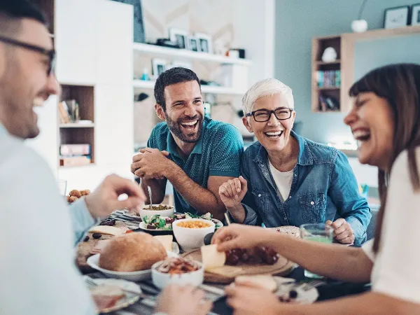 Quatre personnes riantes sont assises à une table dressée dans la salle à manger