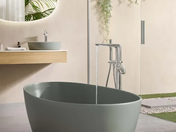 Un bagno a pianta aperta in stile naturale con una vasca freestanding ovale verde.