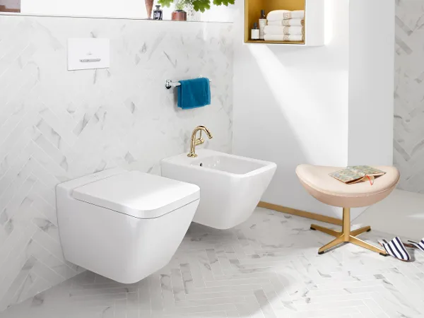 WC e bidet Finion bianchi di Villeroy & Boch con sgabello e pantofole.