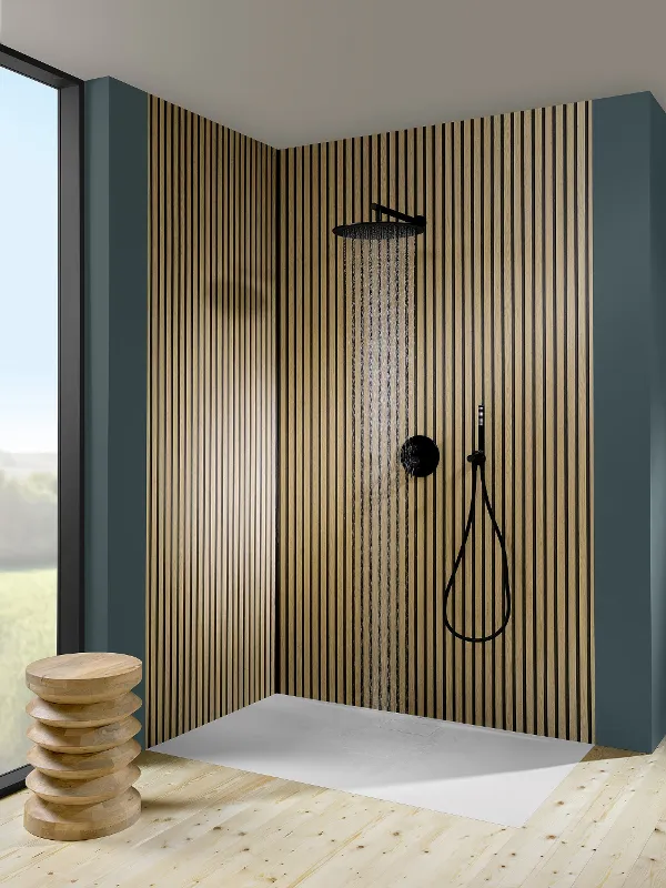 Duschwanne der Badkollektion Architectura in klassisch schönem weiß Moderner Duschbereich mit vertikalen Holzlamellenwänden, dunklen Armaturen und rechteckigem weißen Sockel. Links steht ein Holzhocker und ein großes Fenster bietet den Blick nach draußen.