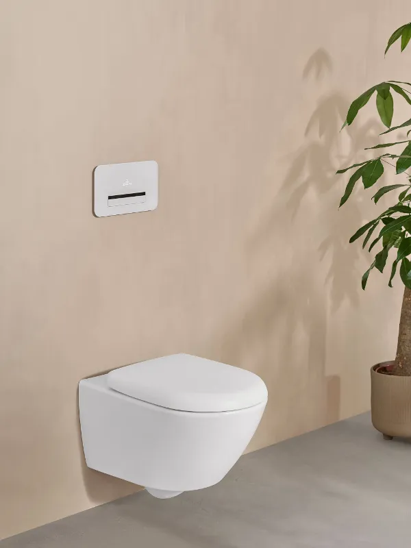 Un WC Antao bianco di Villeroy & Boch in un elegante bagno beige con una pianta in vaso.