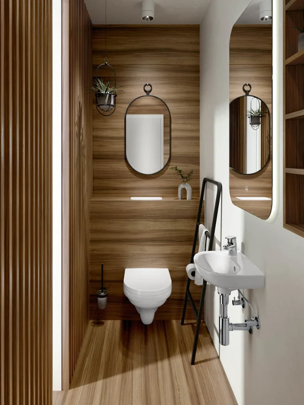 Modern bathroom with wood panelling, a wall-mounted toilet with an oval mirror, a small white washbasin with a large mirror and a shelf with utensils. On the right is a ladder with a black frame for decoration and storage.