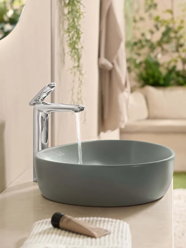 Un lavabo vert de la collection Antao de Villeroy & Boch avec un robinet d’eau qui coule.