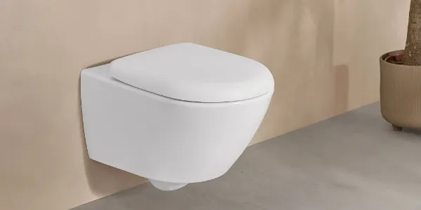 Des toilettes blanches Antao de Villeroy & Boch dans une élégante salle de bains beige avec une plante en pot.