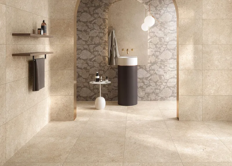 Un bagno elegante con lavabo cilindrico, piastrelle Tri.Art beige, arco a motivi con lampade a sospensione e mensole minimaliste.