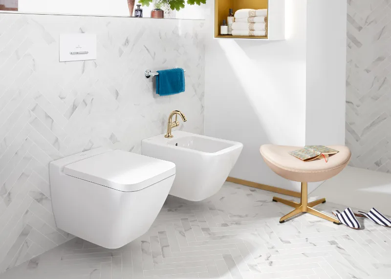 Inodoro y bidé Finion blanco de Villeroy & Boch con taburete y zapatillas.