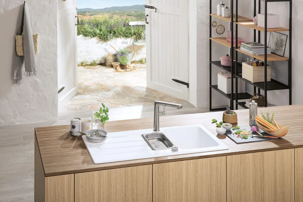 Weiße Architectura Küchenspüle mit Sorano Armatur  in sommerlicher Atmosphäre mit Strandlandschaft im Hintergrund