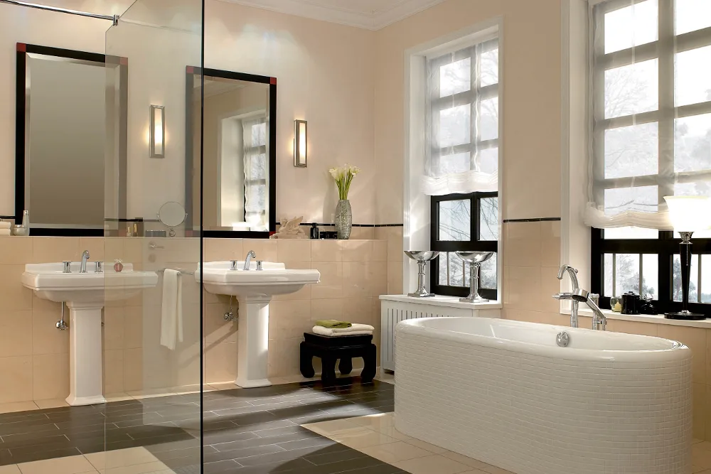 A modern bathroom with a white freestanding bath, two washbasins with a mirror, two large windows and a shower with a glass cabinet.